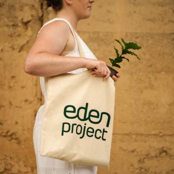 Eden Project tote bag modelled by a woman holding a coffee plant